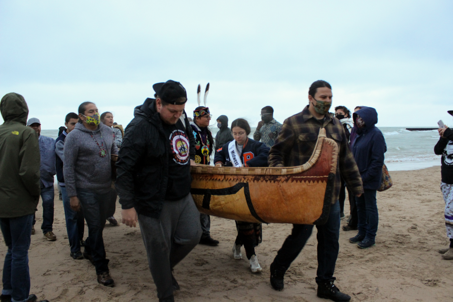 Volunteers carry the canoe on the shore of Lake Michigan.